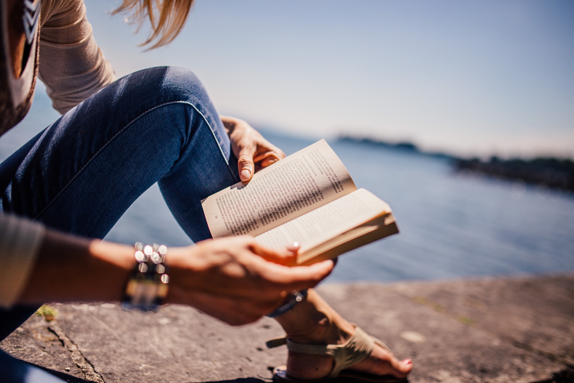 Kvinna läser bok vid havet. Sommartider hej hej